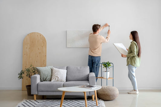 cuplu ce monteaza tablouri canvas pe peretele din living