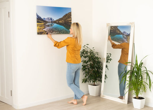 femeie care asaza zambitoare un tablou canvas pe un perete