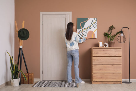 femeie care dispune pe peretele holului locuintei un tablou canvas